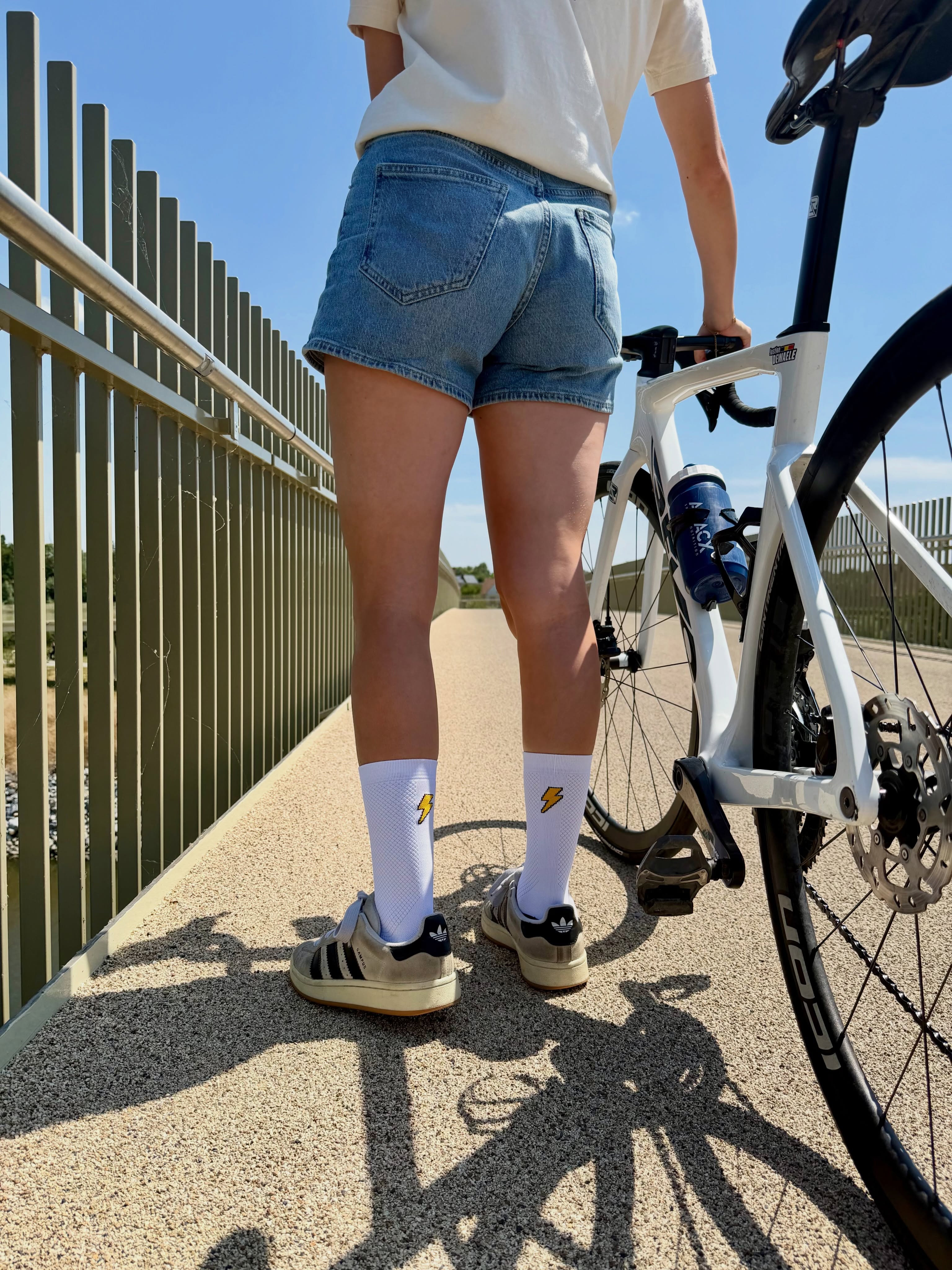 Justine wandelt met haar racefiets over een brug in The Vandal-tee