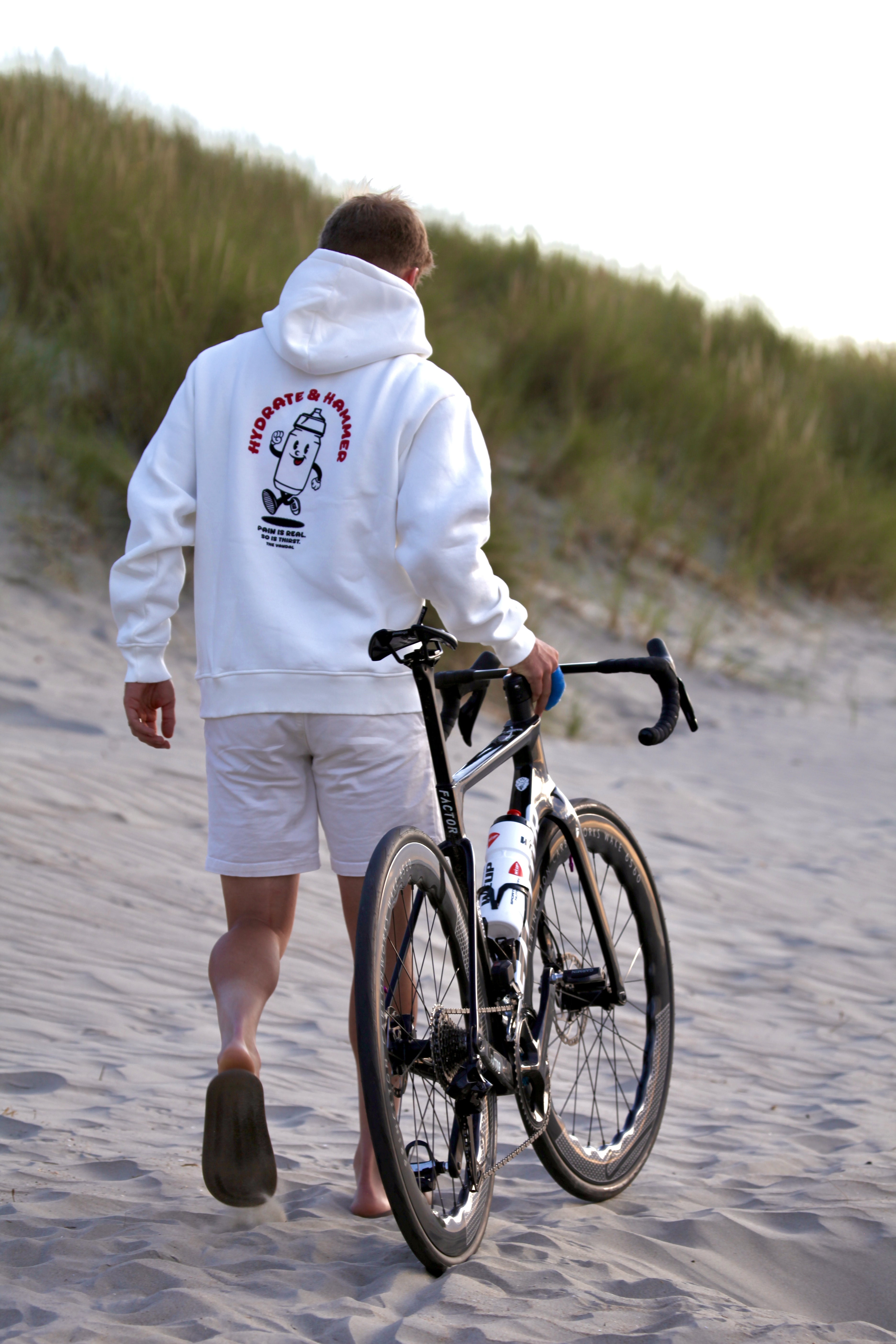 Raynaud wandelt met zijn racefiets door de duinen in The Vandal-hoodie